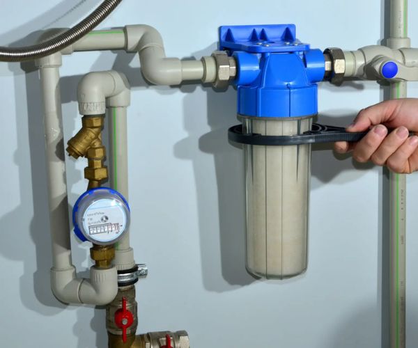 Professional plumber repairing pipes under sink with homeowner watching